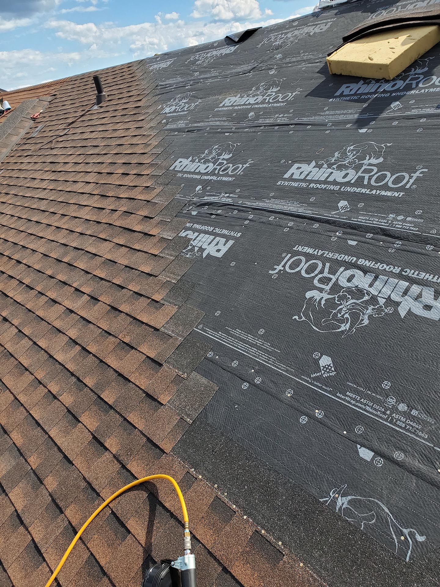 a roof deck covered in synthetic underlay half covered in newbrown shingles